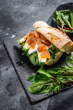 Keçi peynirli baget sandviç, armut reçeli, pazı ve ıspanak. Siyah arka plan. Üst görünüm.