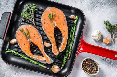 Biberiyeli somon bifteği ve tavada biber. Çiğ organik balık. Gri arka plan. Üst görünüm.