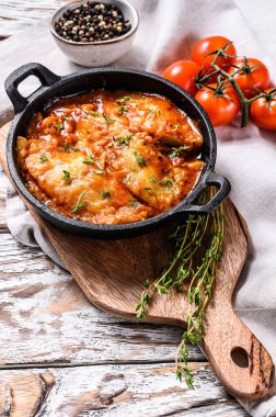 Tavada domatesle pişirilmiş Tilapia balığı. Beyaz ahşap arka plan. Üst görünüm.