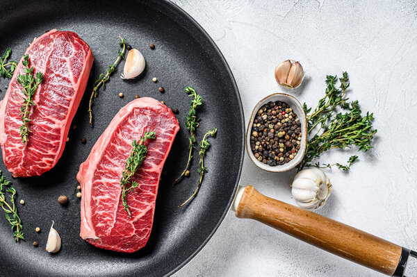 Raw marbled beef steak, top blade meat steak. Gray background. Top view.