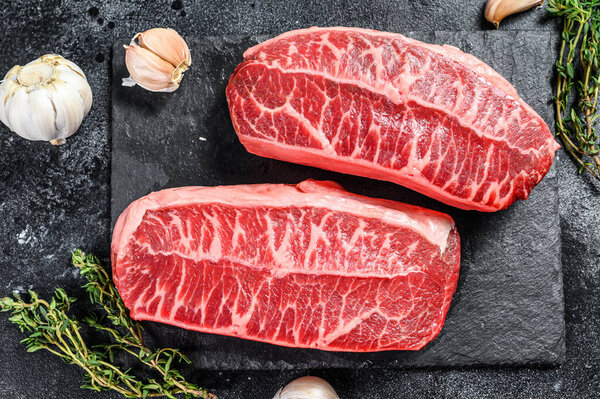 Raw organic meat Twagyu oyster top blade steak. Black background. Top view.