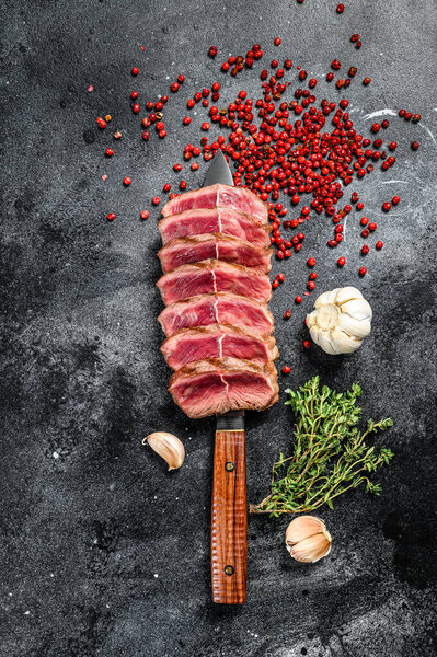 Sliced Grilled Top Blade steak. Organic beef meat. Black background. Top view.
