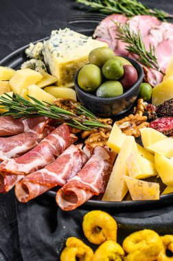 Jambon, prosciutto, salam, mavi peynir, mozarella ve zeytinli Antipasto tabağı. Siyah arka plan. Üst görünüm.