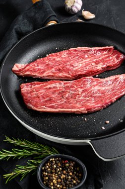 Tavada çiğ biftek var. Siyah mermer Angus eti. Siyah arka plan. Üst görünüm.