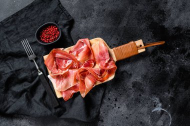 Prosciutto Crudo, İtalyan salamı, parma jambonu. Antipasto tabağı. Siyah arkaplan, üst görünüm, metin için boşluk.