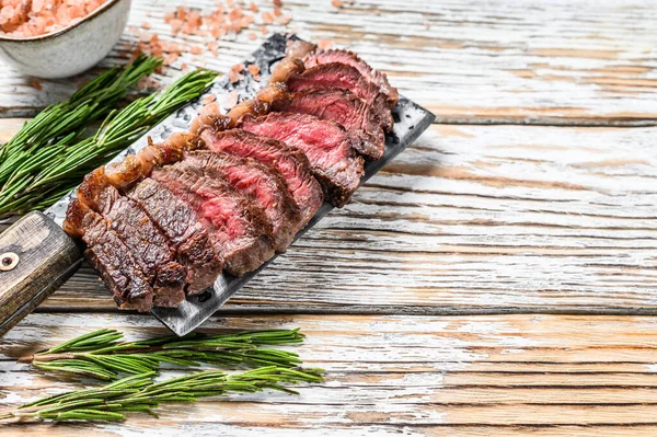 Grilovaná vrchní svíčková nebo pikanha steak na masovém sekáčku s bylinkami. Bílé dřevěné pozadí. Horní pohled. Kopírovat prostor — Stock fotografie