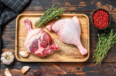 Kesme tahtasındaki ördek bacakları, çiğ et. Karanlık arka plan. Üst görünüm.