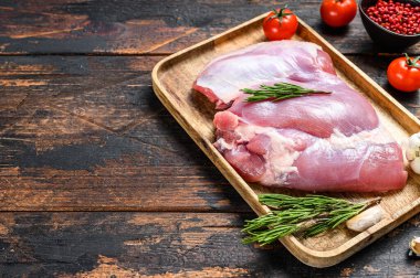 Tahta tepside çiğ kemiksiz hindi filetosu. Karanlık arka plan. Üst Manzara. Boşluğu kopyala.