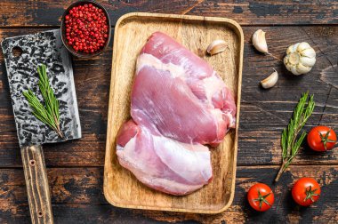 Tahta tepside çiğ kemiksiz hindi filetosu. Karanlık arka plan. Üst görünüm.