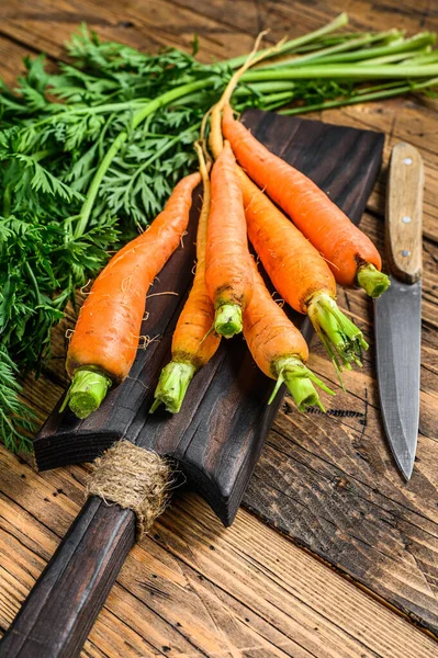 Farmers young carrot with the tops cut off. Wooden background. Top view.