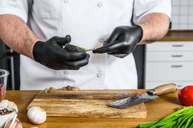 Siyah eldivenli bir şef taze Avacado Hass 'tan guacamole hazırlıyor..