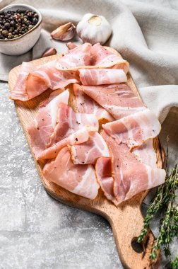 Biberli pastırma ve kekik dilimleme tahtasında. Organik çiğ domuz eti. Gri arka plan. Üst görünüm.