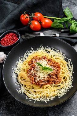 Domatesli spagetti bolonez makarna ve kıyma, parmesan peyniri ve fesleğen. Siyah arka plan. Üst görünüm.