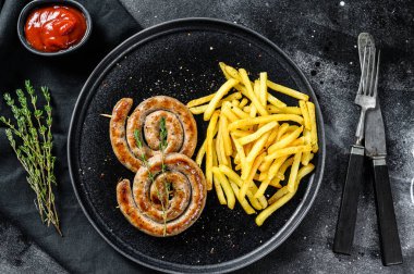 Kızarmış sosis ve yanında patates kızartması. Siyah arka plan. Üst görünüm.