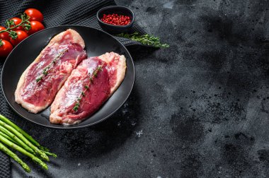 Tabakta çiğ ördek göğsü. Organik kümes hayvanları. Siyah arka plan. Üst Manzara. Boşluğu kopyala.