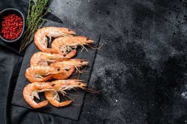Taze kaynamış karidesler, taş tahtada karidesler. Siyah arka plan. Üst Manzara. Boşluğu kopyala.