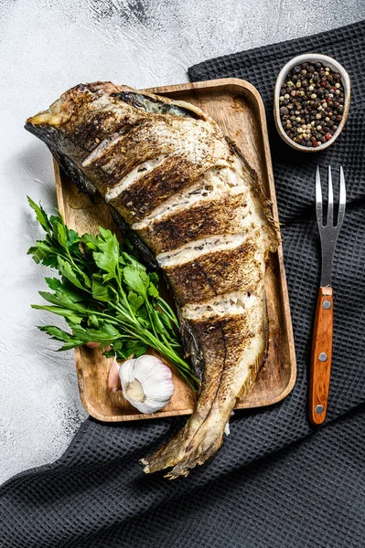 Izgara mezgit balığı pişiriyorum. Gri arka plan. Üst görünüm.