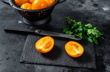 Yarı sarı kiraz domatesi dilimlenmiş. Siyah arka plan. Üst görünüm.