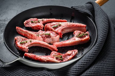 Çiğ kuzu pirzolası, tuzlu, biberli ve tavada otlu. Siyah arka plan. Üst görünüm.