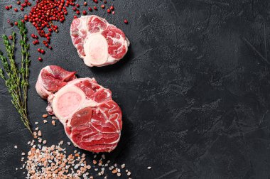 Çiğ taze ossobuco con ve şifalı otlar. Osso Buco eti. Siyah arka plan. Üst Manzara. Boşluğu kopyala.