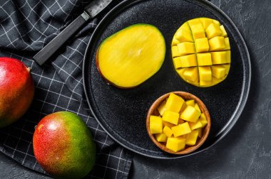 Olgun bir mango. Tropikal meyveleri küp küp doğra. Siyah arka plan. Üst görünüm.