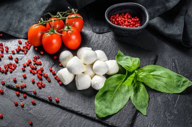 Caprese salatası, mini mozzarella peyniri, fesleğen yaprağı ve vişneli domates. Siyah arka plan. en üstteki görünüm.
