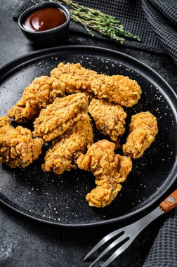 Siyah tabakta kızarmış tavuk kanadı. Siyah arka plan. Üst görünüm.