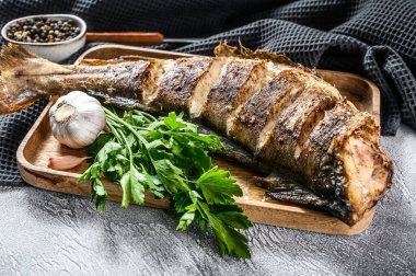 Kesme tahtasında bütün balık mezgit balığı pişirdim. Gri arka plan. Üst görünüm.