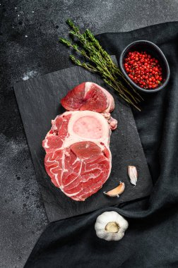 Osso Buco eti. Çiğ dana şişi ve Osso Buco pişirmek için baharat. Siyah arka plan. Üst görünüm.