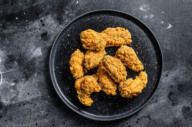 Siyah tabakta kızarmış tavuk kanadı. Siyah arka plan. Üst görünüm.