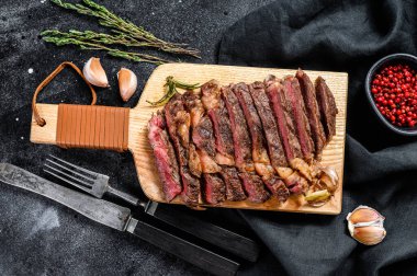 Dilimlenmiş kaburga bifteği, orta pişmiş. Siyah arka plan. Üst Manzara. Boşluğu kopyala.