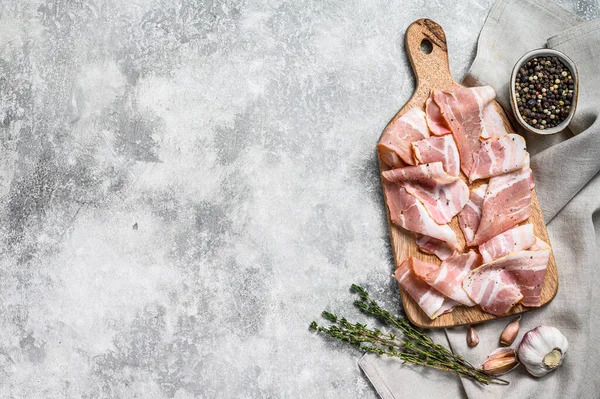 Biberli pastırma ve kekik dilimleme tahtasında. Organik çiğ domuz eti. Gri arka plan. Üst Manzara. Boşluğu kopyala.