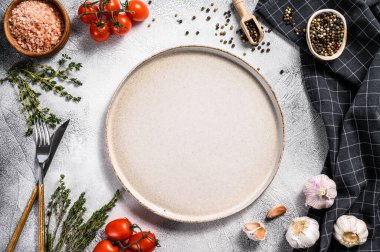 Taze çiğ sebze ve sebzelerin ortasında beyaz boş bir tabak. Sağlıklı, temiz yemek, vejetaryen, diyet yemek konsepti. Beyaz arka plan. Üst Manzara. Boşluğu kopyala.