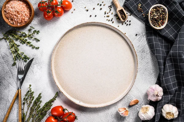 Taze çiğ sebze ve sebzelerin ortasında beyaz boş bir tabak. Sağlıklı, temiz yemek, vejetaryen, diyet yemek konsepti. Beyaz arka plan. Üst Manzara. Boşluğu kopyala.