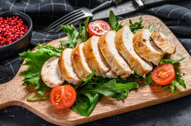 Izgara tavuk göğsü, roka ve domatesli taze salata. Siyah arka plan. Üst görünüm.