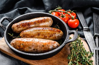 Dökme demir tavada domuz sosisi. Siyah arka plan. Üst görünüm.