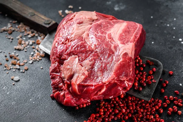 Raw Chuck eye roll steak on meat cleaver. Organic beef. Black background. Top view.