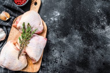 Kesme tahtasında derisi olan taze tavuk budu, organik et. Siyah arka plan. Üst Manzara. Boşluğu kopyala.