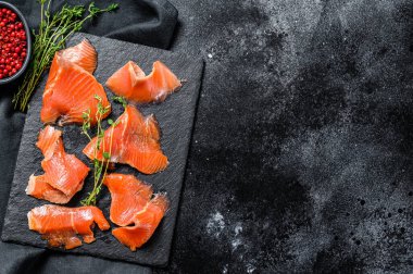 Biber ve kekik ile tuzlanmış somon dilimleri. Organik balık. Siyah arka plan. Üst Manzara. Boşluğu kopyala.