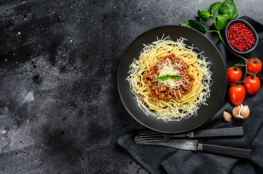 Domates soslu İtalyan spagettisi, peynirli parmesan ve fesleğen. Siyah arka plan. Üst Manzara. Boşluğu kopyala.
