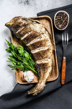 Izgara mezgit balığı pişiriyorum. Gri arka plan. Üst görünüm.