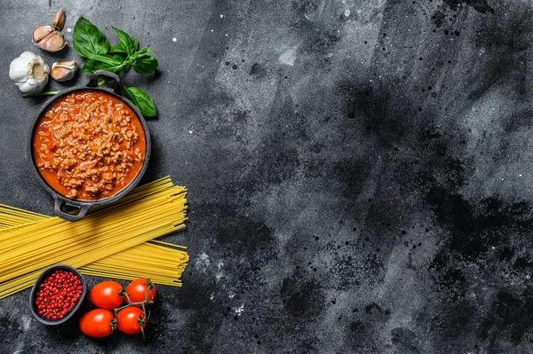 Domatesli makarna, bolonez soslu, peynirli ve fesleğenli makarna pişirme fikri. Siyah arka plan. Üst Manzara. Boşluğu kopyala.