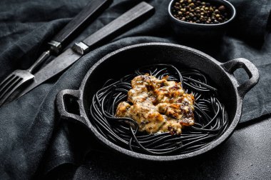 Tavada mürekkep balığı mürekkebi olan siyah spagetti makarna. Biber soslu biftek. Siyah arka plan. Üst görünüm.