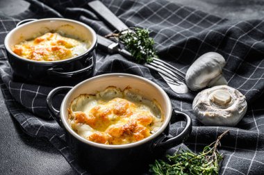 Kil kapta peynirli tavuk ve mantar güveci. Siyah arka plan. Üst görünüm.