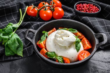 Burrata mozzarella, vişneli domates ve fesleğenli Caprese salatası. Siyah arka plan. Üst görünüm.