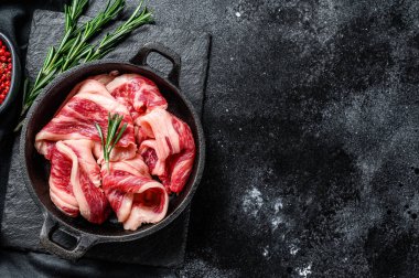 Çiğ pastırma, tavada mermer et şeritleri. Siyah arka plan. Üst Manzara. Boşluğu kopyala.