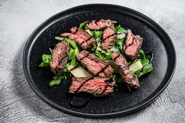 Ispanaklı biftek salatası, roka ve dilimlenmiş biftek. Gri arka plan. Üst görünüm.