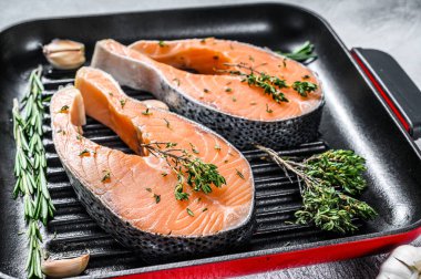 Biberiyeli somon bifteği ve tavada biber. Çiğ organik balık. Gri arka plan. Üst görünüm.