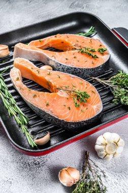 Biberiyeli somon bifteği ve tavada biber. Çiğ organik balık. Gri arka plan. Üst görünüm.