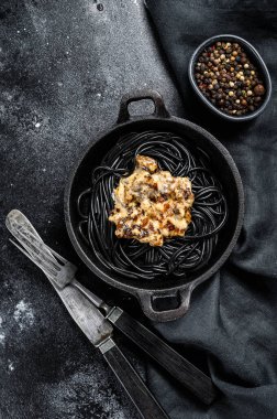 Krema soslu somonlu siyah spagetti makarna. Siyah arka plan. Üst görünüm.